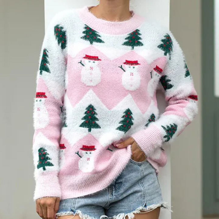 Roze kersttrui met sneeuwpop- en kerstboomprint, gedragen door persoon in spijkershorts. Perfect voor feestdagen, wintermode, casual stijl.