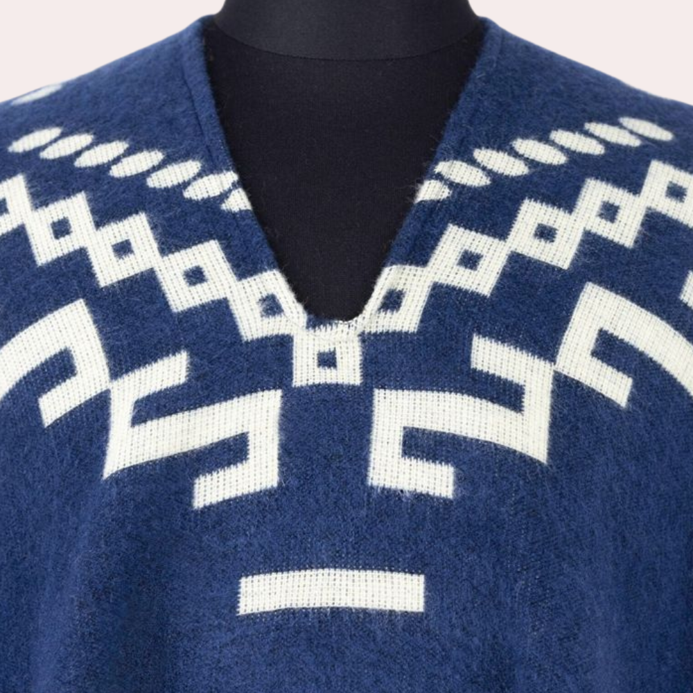 Blauwe alpaca poncho met witte geometrische patronen, V-hals. Handgemaakt, warme wintermode, etnisch design, duurzame kleding.