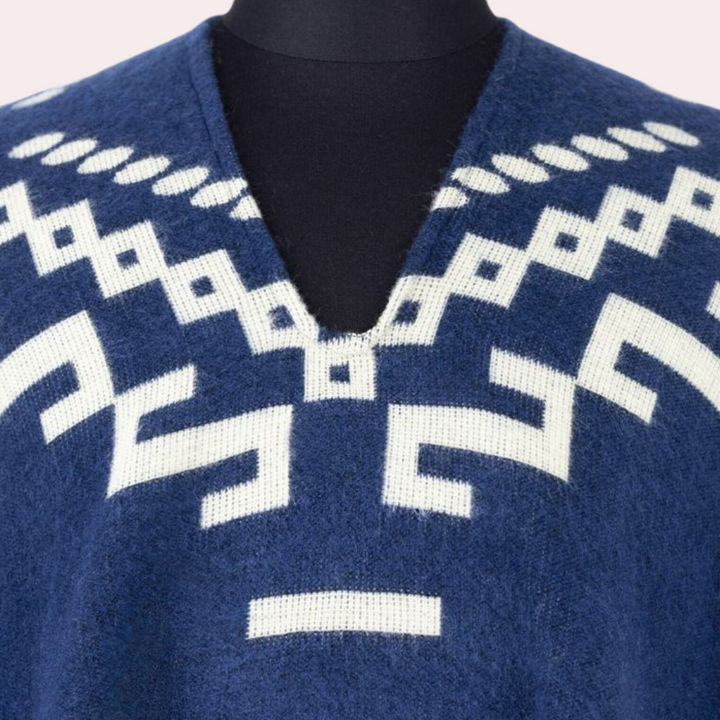 Blauwe alpaca poncho met witte geometrische patronen, V-hals. Handgemaakt, warme wintermode, etnisch design, duurzame kleding.
