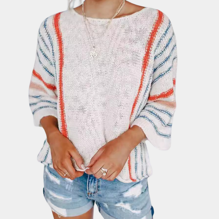Vrouw draagt witte trui met oranje en blauwe strepen, driekwart mouwen, gecombineerd met gescheurde denim shorts. Casual damesmode, zomeroutfit.