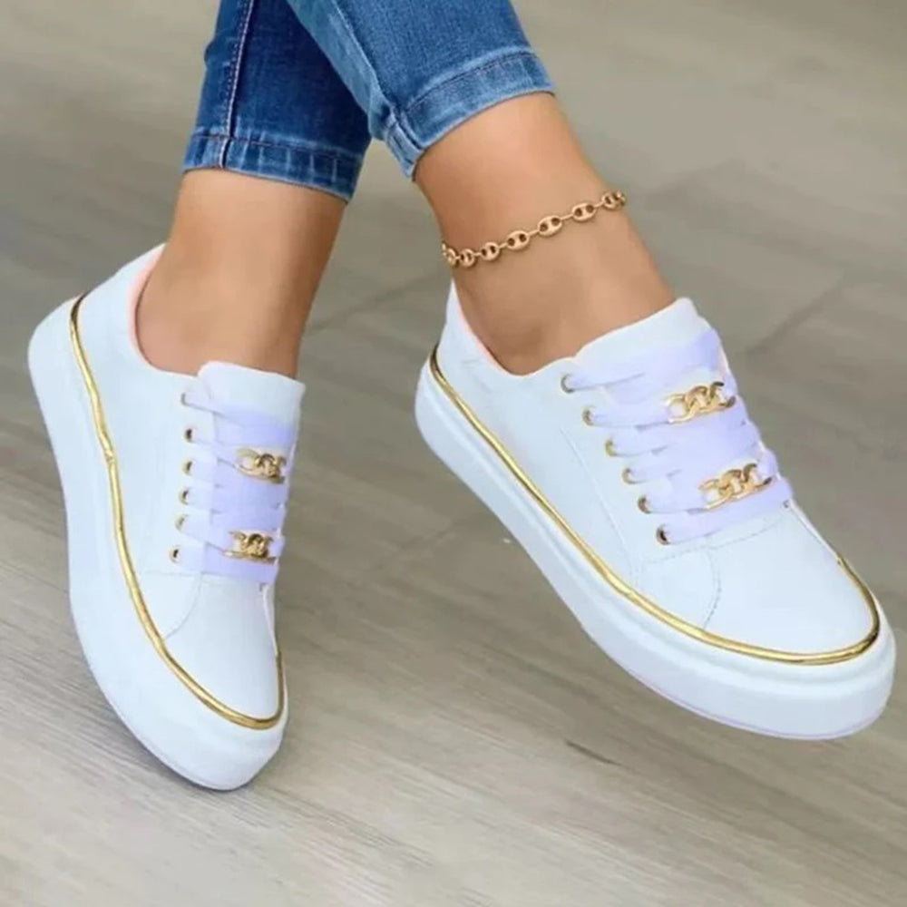 Witte dames sneakers met gouden details en ketting, gedragen met blauwe jeans. Stijlvolle casual schoenen voor dagelijks gebruik.