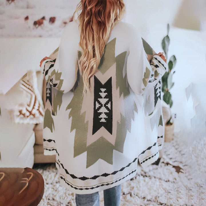 Vrouw in witte, geometrisch gebreide cardigan met Azteekse print, casual interieur, boho-stijl, comfortabele mode, herfstkleding.
