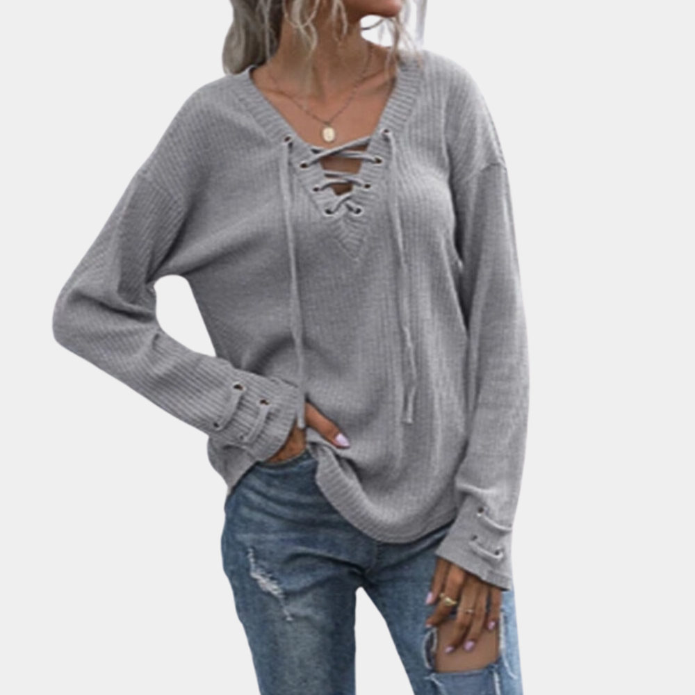Grijze damestrui met vetersluiting, lange mouwen en casual pasvorm, gecombineerd met gescheurde jeans. Perfect voor herfstmode en casual outfits.
