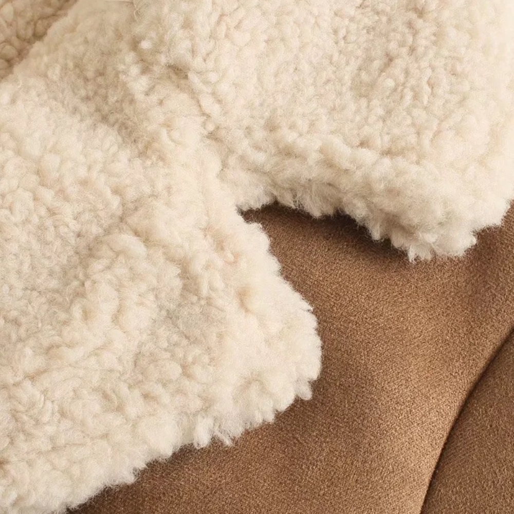 Beige schapenvacht deken op bruine suède bank; zachte, warme texturen; interieurdecoratie; knusse woonaccessoires; wintercomfort.