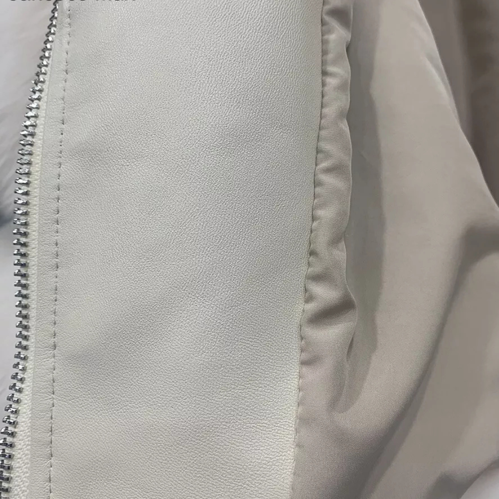 Grijze leren jas close-up met zilveren ritssluiting, gladde textuur. Modieuze damesjas, hoogwaardige materialen, trendy design.