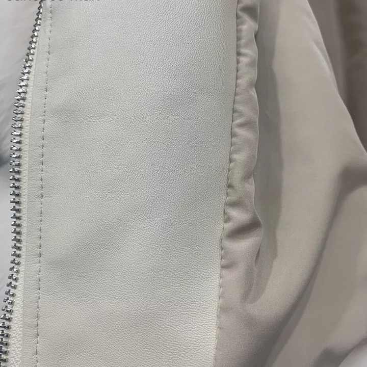 Grijze leren jas close-up met zilveren ritssluiting, gladde textuur. Modieuze damesjas, hoogwaardige materialen, trendy design.