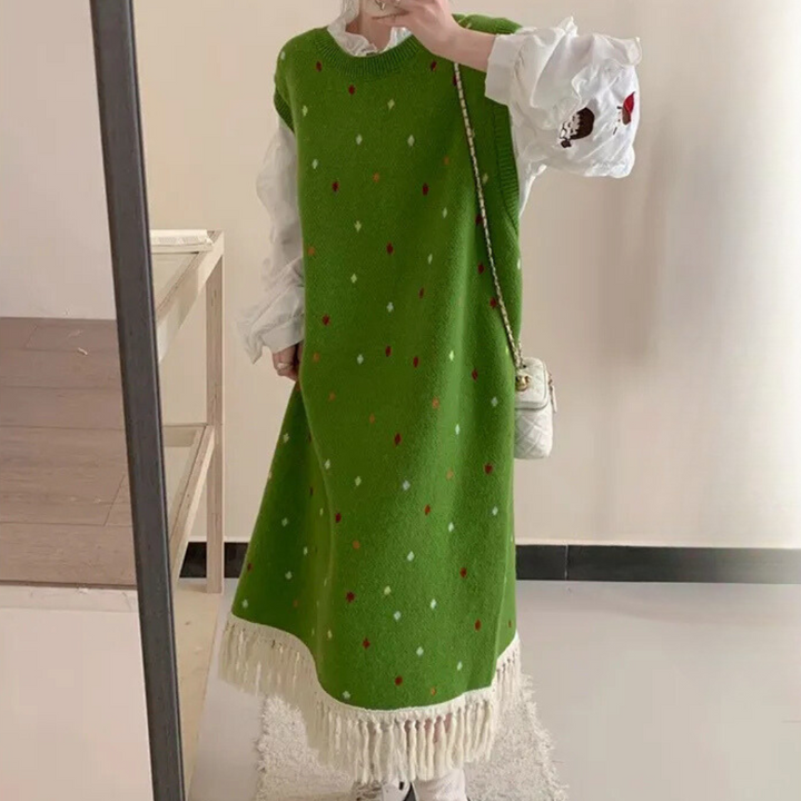 Groene gebreide jurk met kleurrijke stippen en franjes, gedragen over een witte blouse. Modieuze dameskleding, herfst-winter outfit.