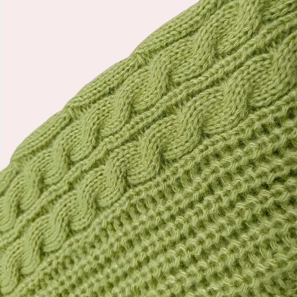 Groene gebreide kabeltrui textuur, close-up. Zachte wol, modieuze winterkleding, warme gebreide stof, trendy kledingstuk, comfortabele stijl.
