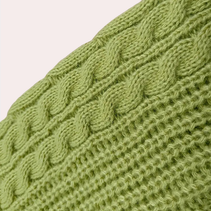 Groene gebreide kabeltrui textuur, close-up. Zachte wol, modieuze winterkleding, warme gebreide stof, trendy kledingstuk, comfortabele stijl.