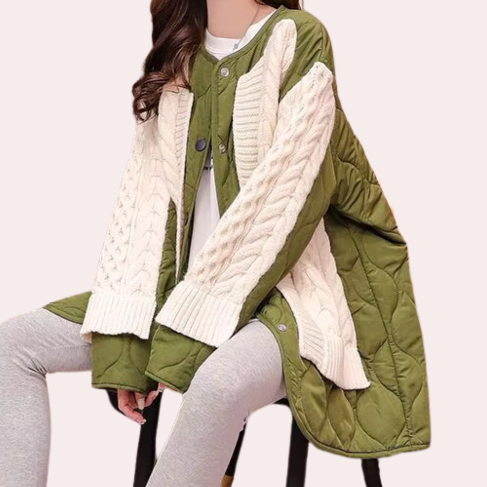 Groene gewatteerde jas met witte gebreide mouwen, gedragen door zittend model. Modieuze damesjas, herfst-winter stijl, comfortabele pasvorm.