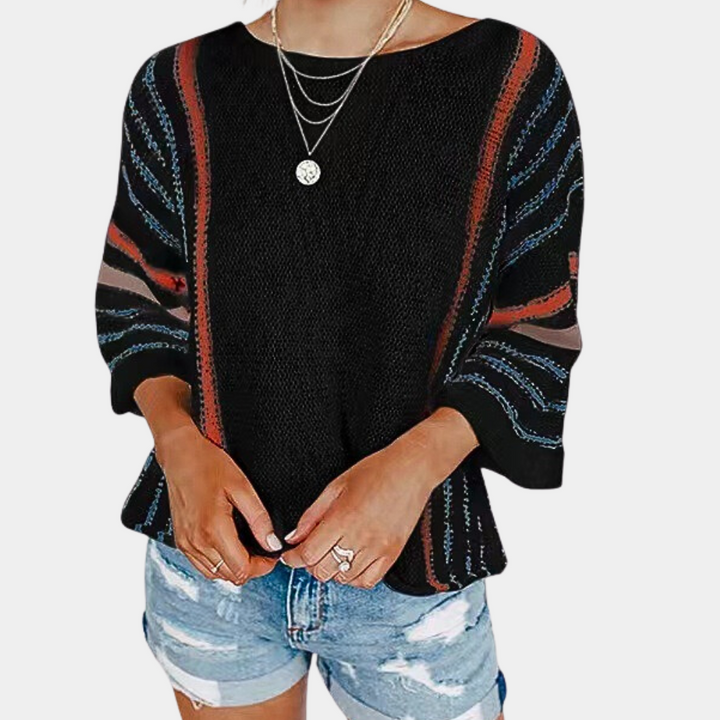 Zwarte gebreide trui met kleurrijke strepen, driekwart mouwen en ronde hals, gedragen door model met denim shorts en kettingen.