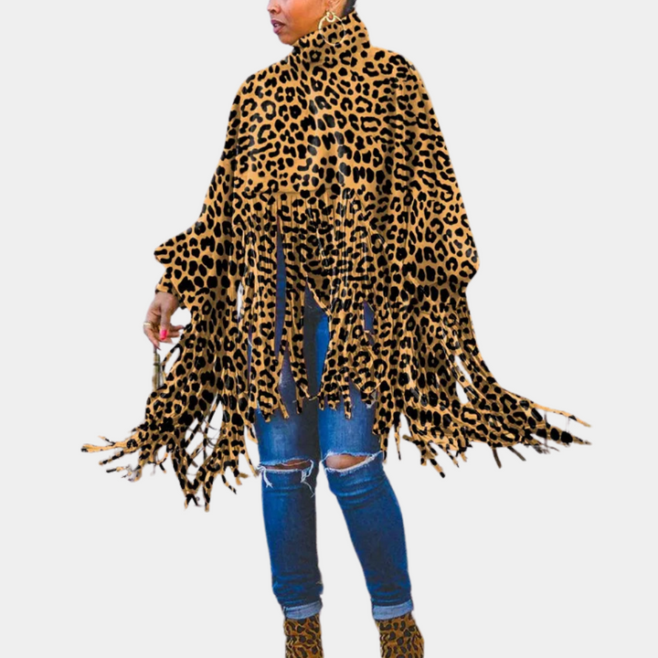 Vrouw draagt een luipaardprint poncho met franjes, gecombineerd met gescheurde jeans en bijpassende laarzen. Modieuze herfstoutfit, trendy dierenprint.