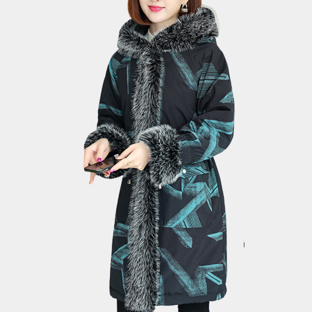 Vrouw in stijlvolle winterjas met bontkraag en abstract patroon, zwart met turquoise accenten, houdt smartphone vast. Modieuze dameskleding.