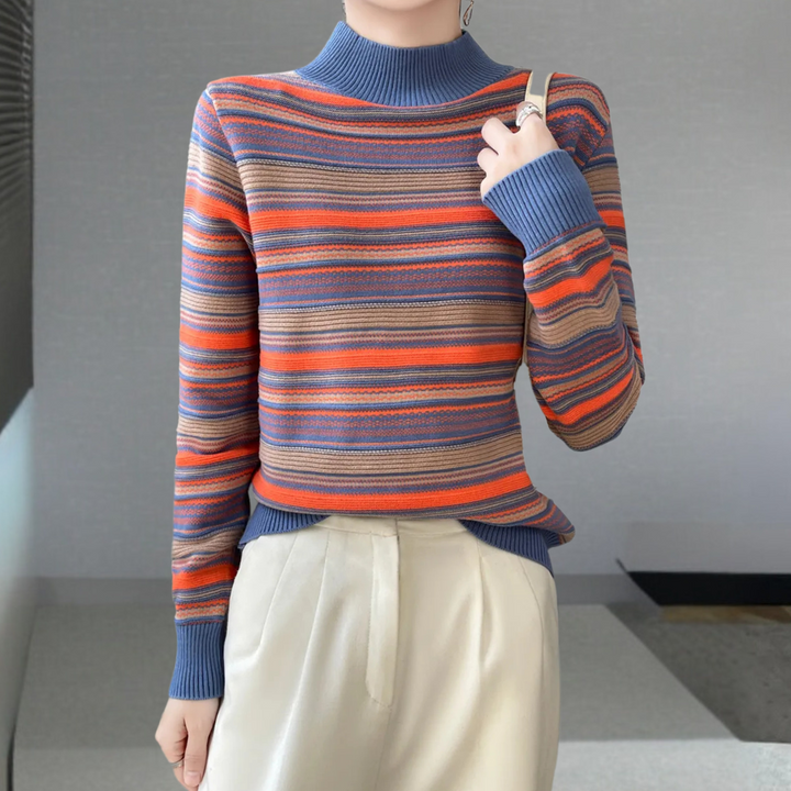 Gestreepte damestrui in blauw, oranje en bruin, gecombineerd met crèmekleurige broek. Modieuze herfstkleding, comfortabele casual stijl.