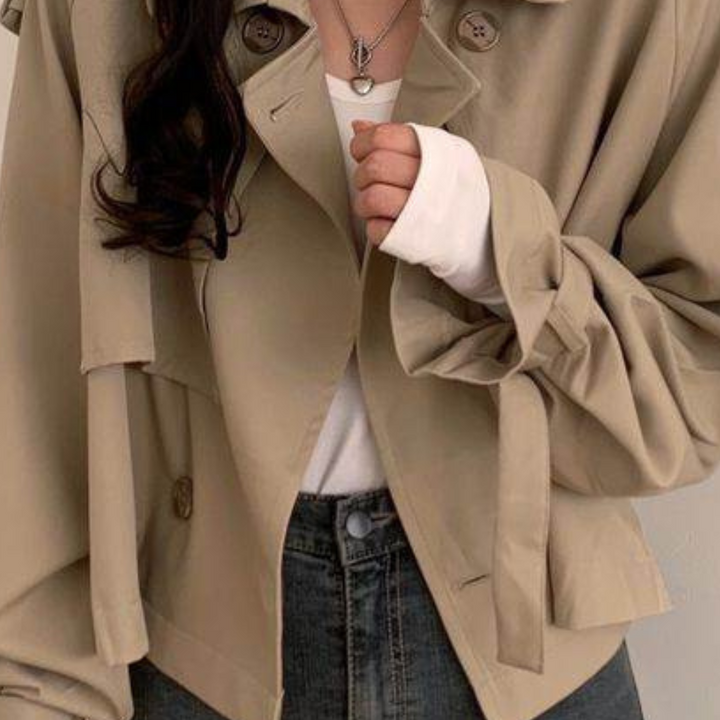 Beige trenchcoat met knoopdetails, gedragen over een witte trui en spijkerbroek. Modieuze herfstkleding, casual stijl, damesmode.