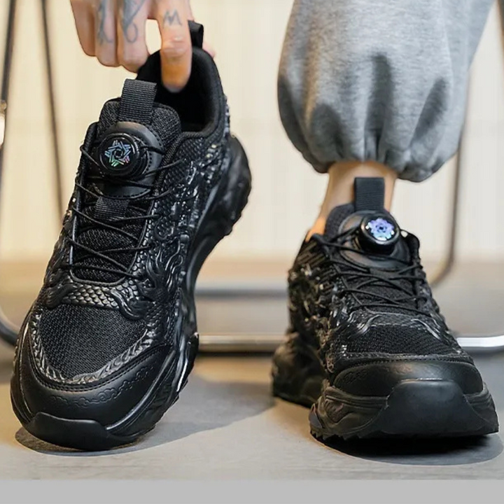 Zwarte sportschoenen met dikke zool en uniek patroon, gedragen door persoon in grijze joggingbroek. Trendy sneakers voor heren, comfortabele pasvorm.