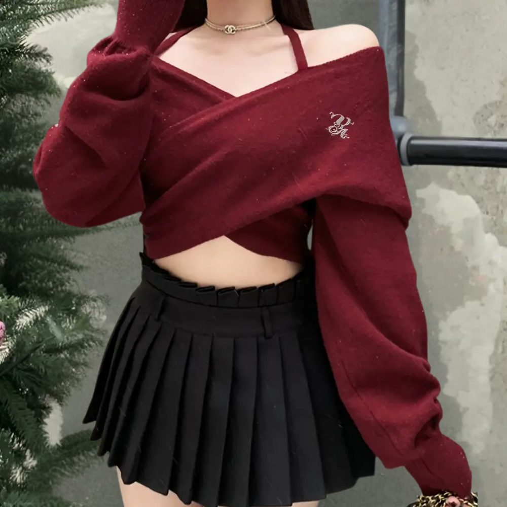 Vrouw in bordeauxrode off-shoulder trui en zwarte geplooide minirok, trendy wintermode, casual chique outfit, kerstboom op achtergrond.