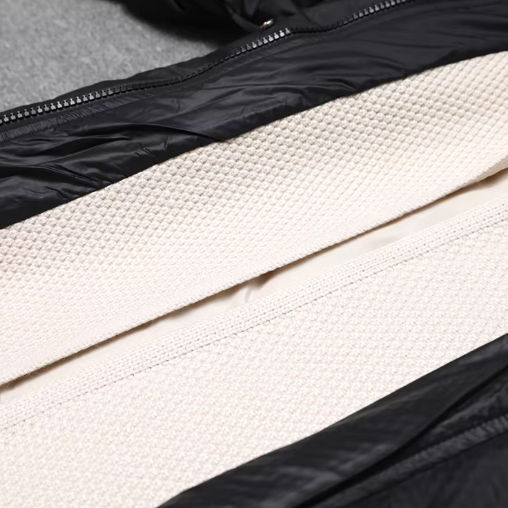 Zwarte gewatteerde jas met crèmekleurige voering, ritssluiting en textuurdetail. Ideaal voor wintermode en outdooractiviteiten.