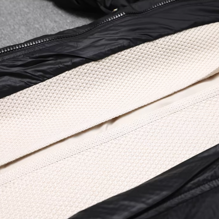 Zwarte gewatteerde jas met crèmekleurige voering, ritssluiting en textuurdetail. Ideaal voor wintermode en outdooractiviteiten.