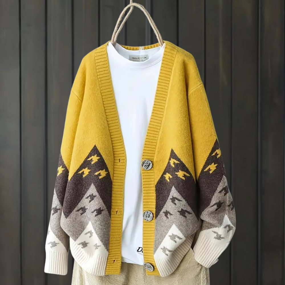 Geel-bruine oversized cardigan met geometrisch patroon, hangend voor een houten achtergrond. Trendy herfstmode, comfortabele dameskleding.