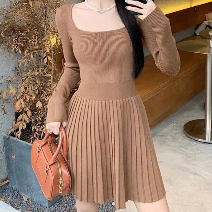 Vrouw in bruine geribbelde jurk met lange mouwen en plissé rok, draagt een bruine handtas. Stijlvolle herfstmode, casual chique outfit.