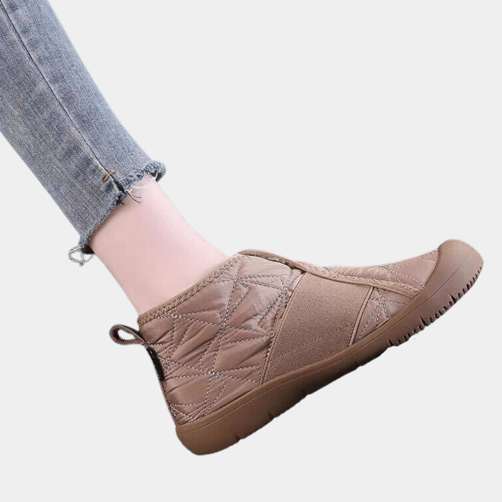 Bruine, gewatteerde enkellaars met rubberen zool en gestikte details, gedragen met een opgerolde spijkerbroek. Comfortabele damesmode, casual stijl.