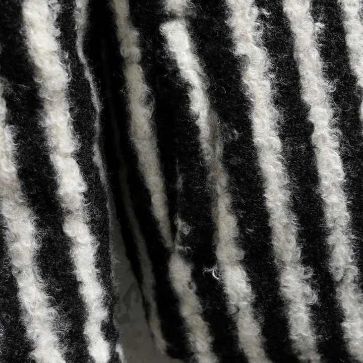 Zwart-wit gestreepte wollen stof close-up, textuur van gebreide wol, modieuze winterkleding, warme en comfortabele materialen.