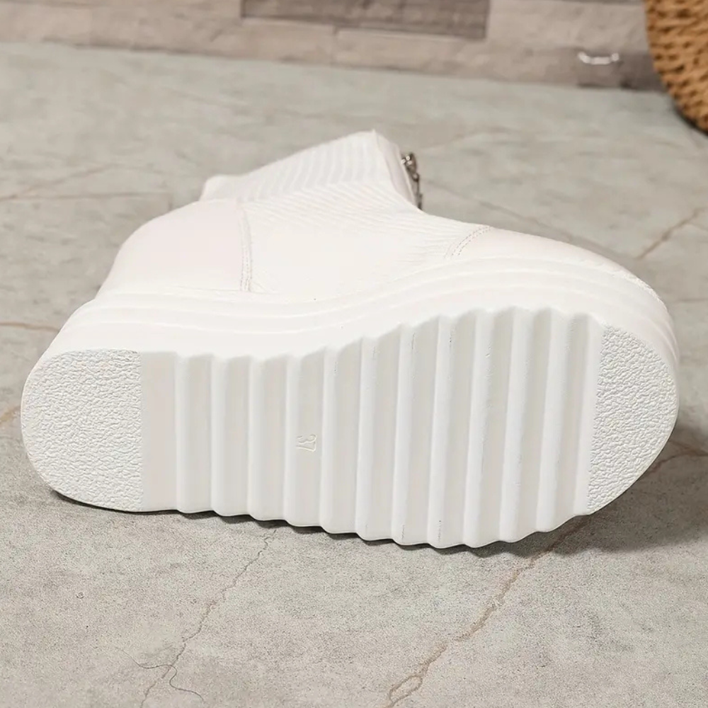Witte platformlaars met geribbelde zool, zijrits en modern design op grijze achtergrond. Trendy damesmode, comfortabele schoenen, herfst/winterstijl.