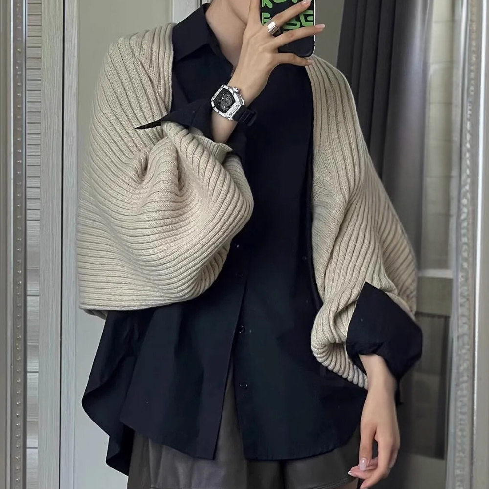 Persoon draagt zwarte blouse met beige gebreide sjaal en zilveren horloge, spiegelselfie. Modieuze herfstoutfit, casual chique stijl.