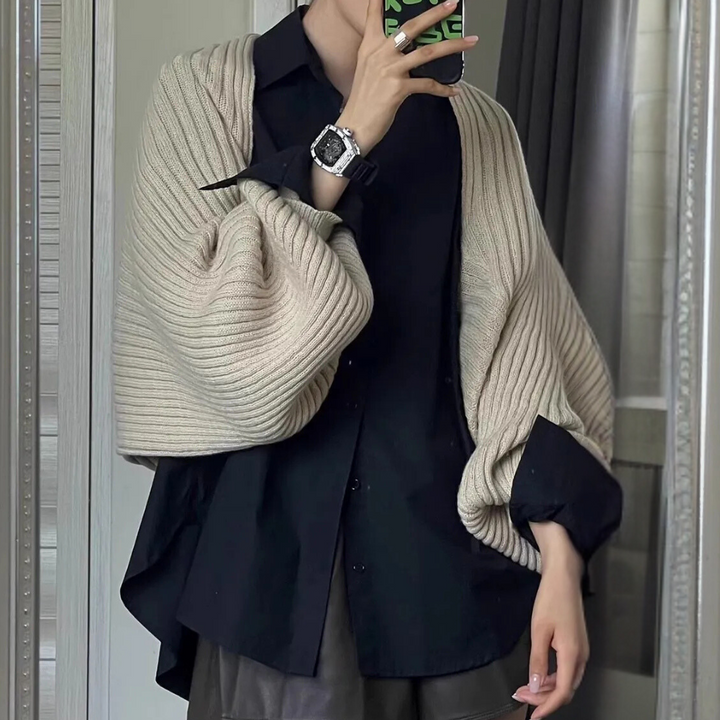 Persoon draagt zwarte blouse met beige gebreide sjaal en zilveren horloge, spiegelselfie. Modieuze herfstoutfit, casual chique stijl.