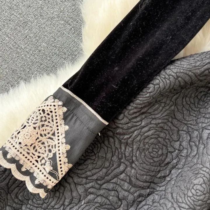 Zwarte fluwelen mouw met kanten manchet op grijze rozenstof en witte bontdeken, elegante mode, textuur en detail.