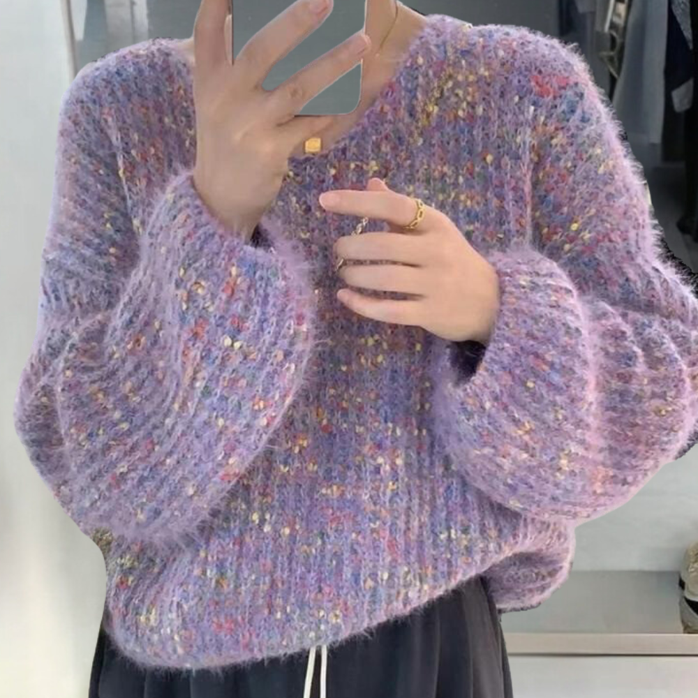 Paarse gebreide trui met kleurrijke stippen, oversized pasvorm, gedragen door persoon die smartphone vasthoudt. Modieuze winterkleding, trendy design.