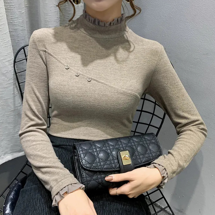 Vrouw in beige coltrui met knopen, houdt een zwarte, gewatteerde handtas vast. Elegante mode, herfstkleding, damesaccessoires.