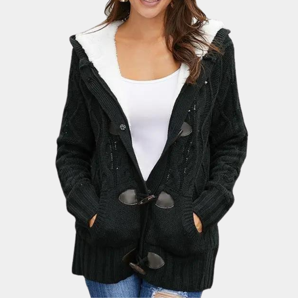 Zwarte gebreide damesvest met capuchon, houten knopen en zakken, gedragen over een witte top. Perfect voor casual herfst- en winteroutfits.