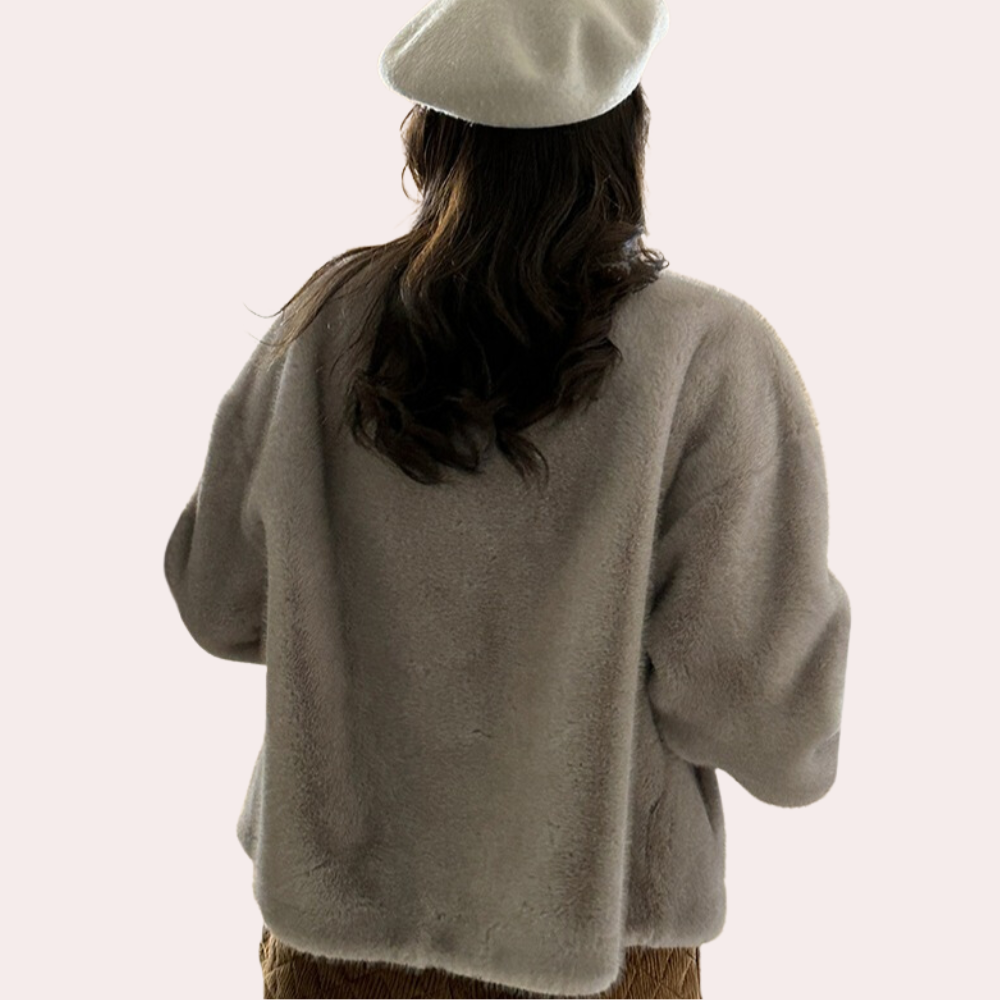 Vrouw in beige faux fur jas en witte baret, rugaanzicht. Modieuze winterkleding, trendy damesmode, warme jas, stijlvolle accessoires.