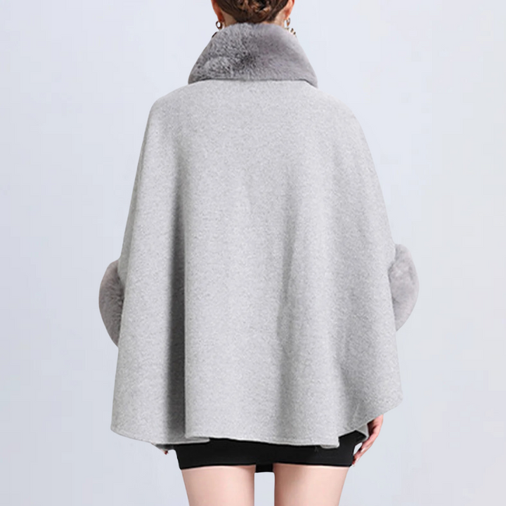 Grijze damescape met bontkraag, elegante wintermode, stijlvolle warme mantel, trendy kleding voor koude seizoenen, modieuze damesoutfit.