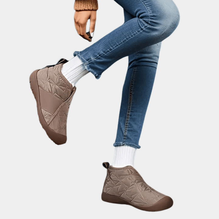 Beige winterlaarzen voor dames, waterdicht en gevoerd, gedragen met blauwe jeans en witte sokken. Comfortabele en warme schoenen voor koud weer.