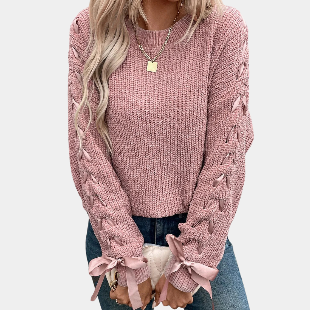 Vrouw in roze gebreide trui met vlechtpatroon en strikdetails, casual mode, trendy dameskleding, herfstoutfit, lange mouwen, stijlvolle look.
