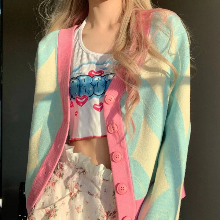 Vrouw in pastel gekleurde cardigan met roze knopen, wit topje met blauwe tekst en bloemenrok. Trendy damesmode, casual lente outfit.