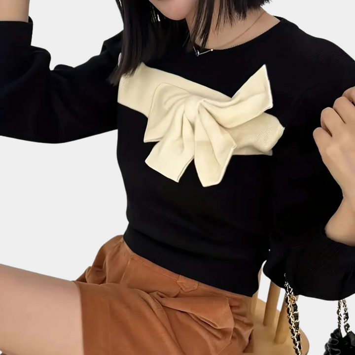 Zwarte trui met opvallende witte strik, gedragen door vrouw. Modieuze dameskleding, herfststijl, casual chic outfit.