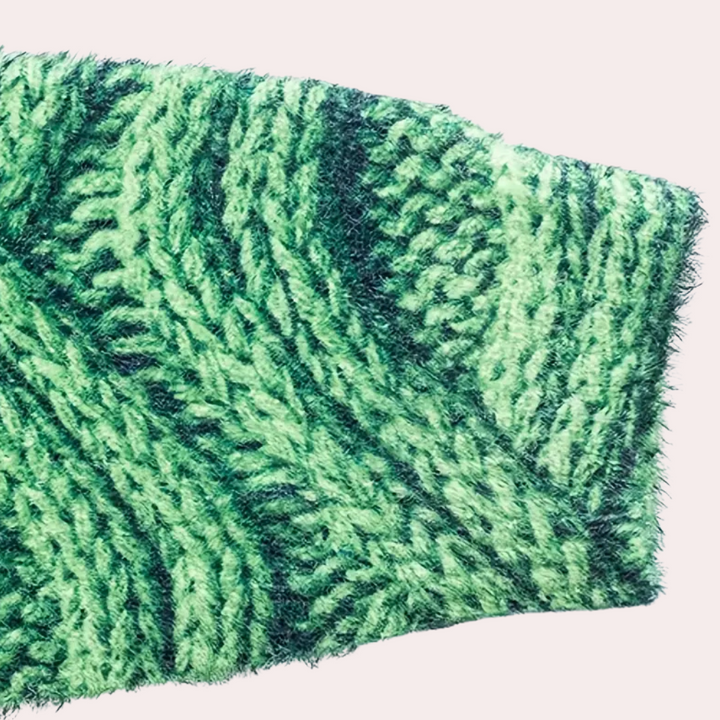 Groene gebreide trui met kabelpatroon, close-up. Zachte, warme stof, ideaal voor wintermode. Trendy kledingstuk, perfect voor koude dagen.