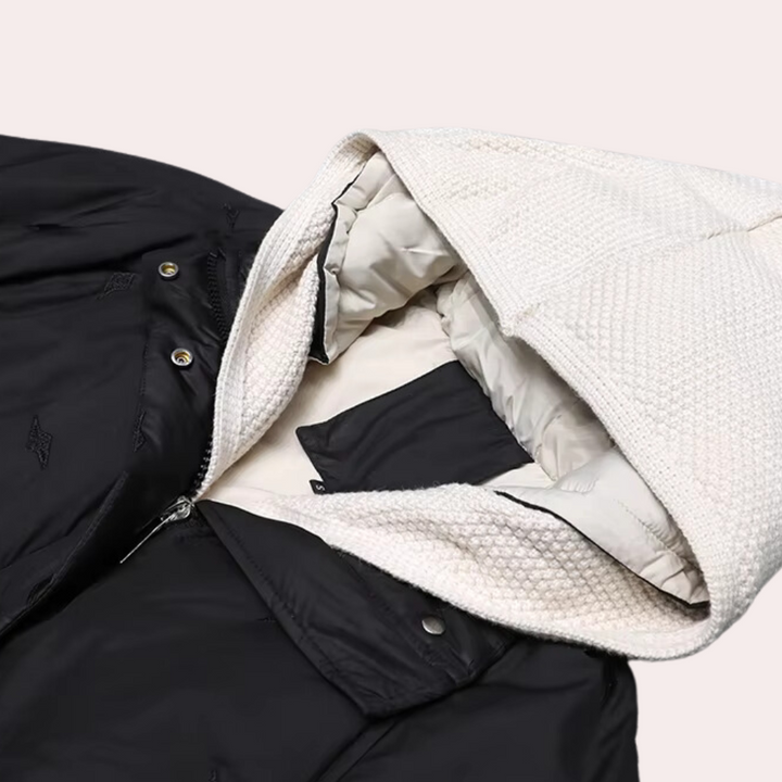 Zwart-witte gewatteerde jas met capuchon, ritssluiting en knopen. Ideaal voor wintermode, biedt warmte en stijl. Unisex ontwerp, trendy en functioneel.