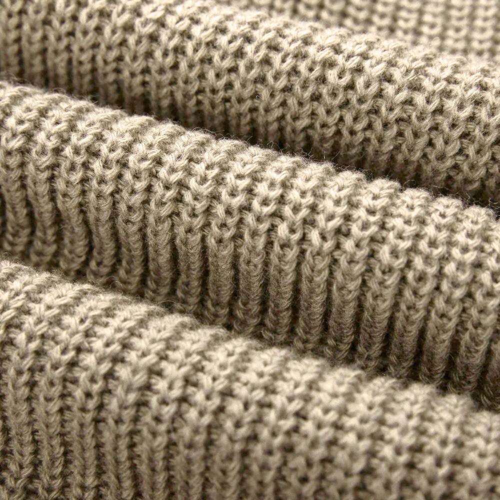 Beige gebreide stof close-up, textuur van wol, geschikt voor truien en winterkleding. Zachte, warme breisel voor mode en interieur.