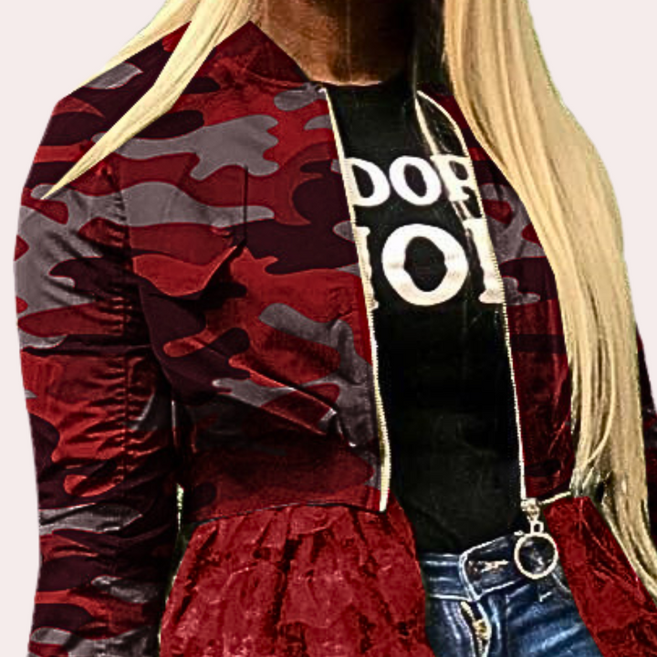 Rood camouflage bomberjack met rits, gedragen door vrouw met blond haar, zwarte T-shirt en blauwe jeans. Modieuze dameskleding, urban stijl.