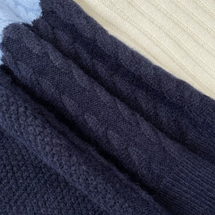 Donkerblauwe gebreide trui met kabelpatroon, close-up. Zachte textuur, warme winterkleding, modieuze herenkleding, comfortabele stof.