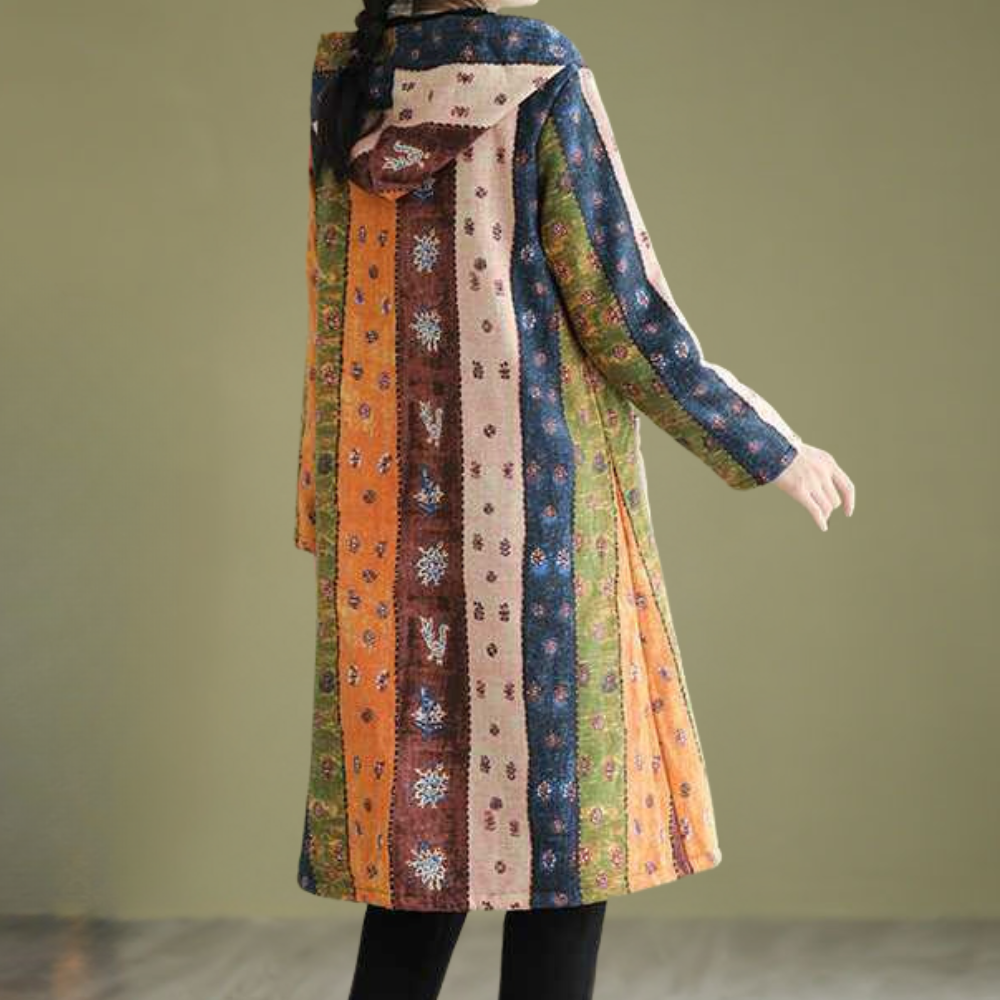 Vrouw in kleurrijke, gestreepte lange jas met capuchon, bohemian stijl, tegen een neutrale achtergrond. Perfect voor herfstmode en casual outfits.