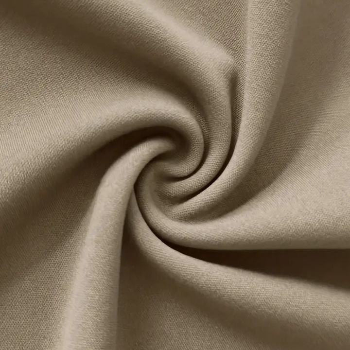 Beige katoenen stof close-up, gedraaid in een spiraalpatroon. Zachte textuur, ideaal voor kleding en interieurdecoratie. Hoogwaardige textielmaterialen.