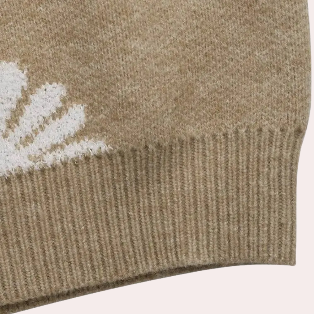 Beige wollen trui met witte bloemprint, close-up van de zoom. Zachte, warme stof, ideaal voor herfst- en wintermode. Comfortabele casual stijl.