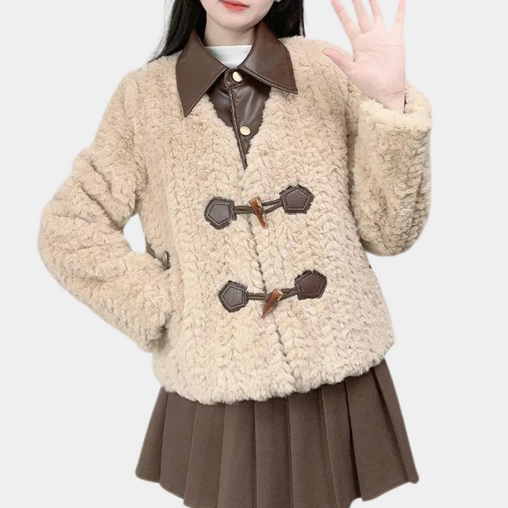 Vrouw in beige teddyjas met bruine leren kraag en knopen, gecombineerd met bruine plooirok. Modieuze winterkleding, trendy damesmode.