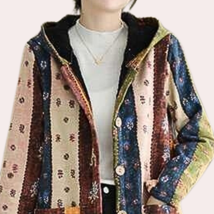 Vrouw draagt kleurrijke, gestreepte patchwork jas met capuchon en knopen. Boho-stijl, casual mode, herfstkleding, unieke vintage look.